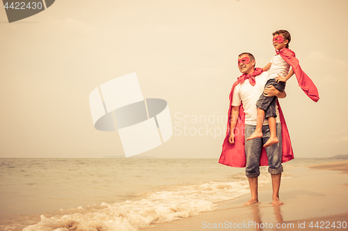 Image of Father and son playing superhero on the beach at the day time.