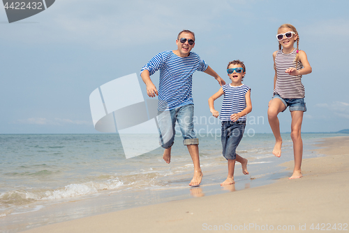 Image of Father and children  playing on the beach at the day time.