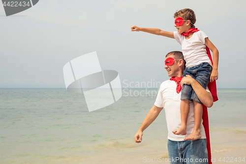 Image of Father and son playing superhero on the beach at the day time.