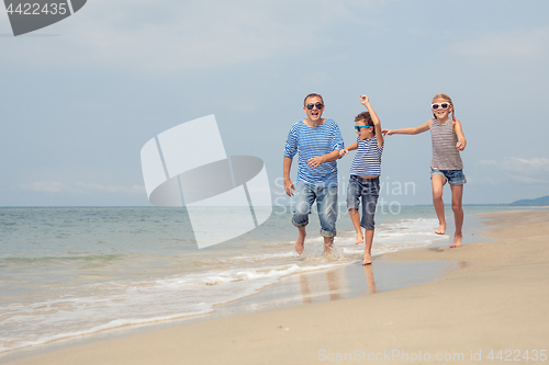 Image of Father and children  playing on the beach at the day time.