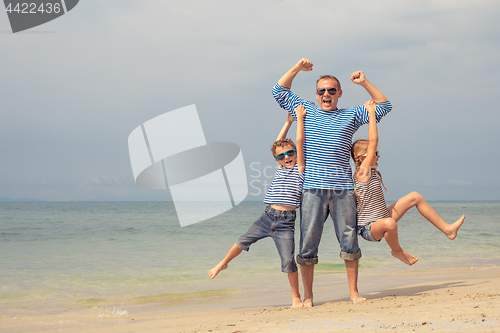 Image of Father and children  playing on the beach at the day time.