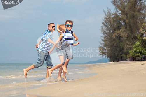 Image of Father and children  playing on the beach at the day time.