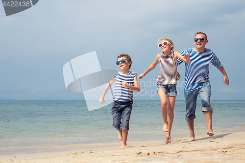 Image of Father and children  playing on the beach at the day time.