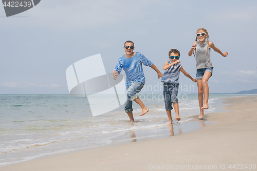 Image of Father and children  playing on the beach at the day time.