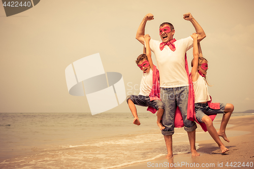 Image of Father and children playing superhero on the beach at the day ti