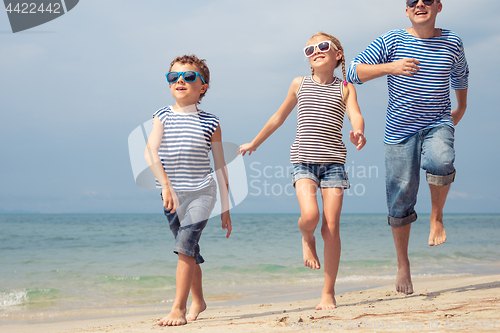 Image of Father and kids running on the beach at the day time. 