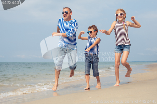 Image of Father and children  playing on the beach at the day time.