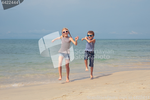 Image of Two happy little children playing on the beach at the day time. 