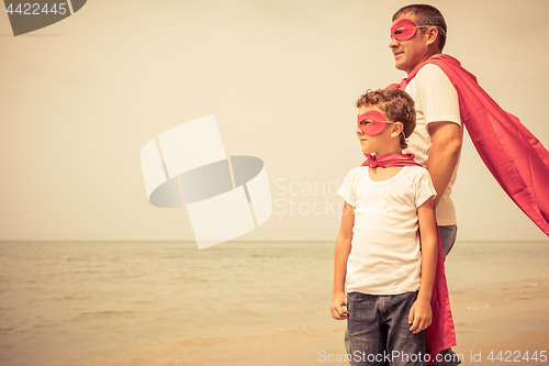 Image of Father and son playing superhero on the beach at the day time.