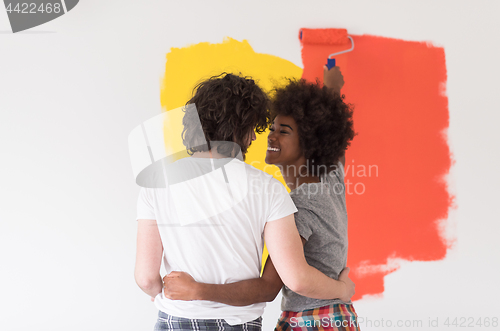 Image of multiethnic couple painting interior wall