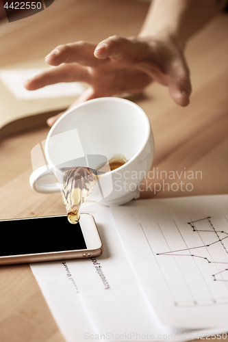 Image of Coffee in white cup spilling on the table in the morning working day at office table