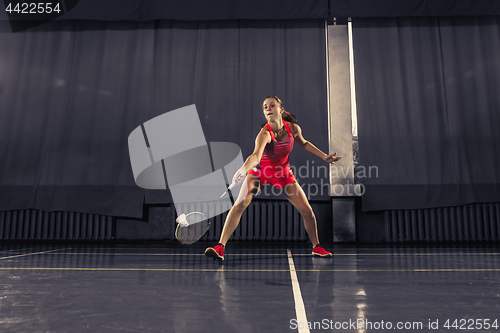 Image of Young woman playing badminton at gym