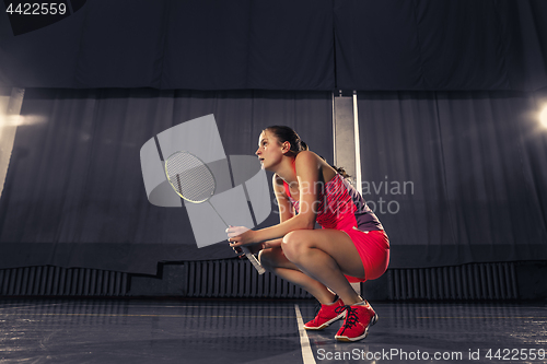 Image of Young woman resting after playing badminton at gym