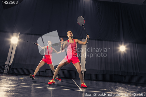 Image of Young women playing badminton at gym