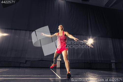 Image of Young woman playing badminton at gym