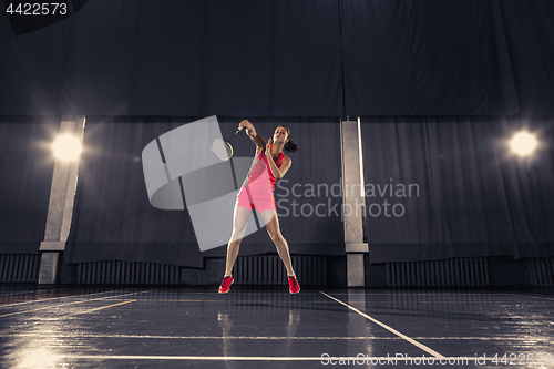 Image of Young woman playing badminton at gym