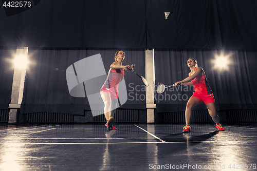 Image of Young women playing badminton at gym