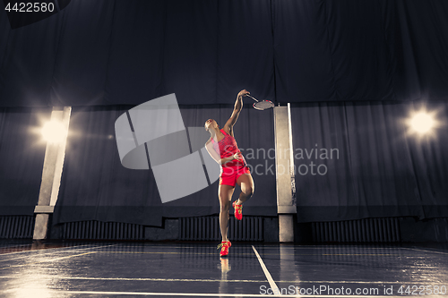 Image of Young woman playing badminton at gym