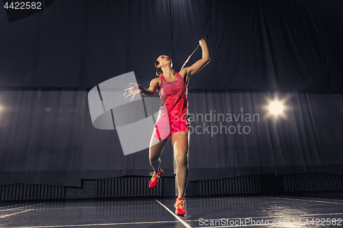 Image of Young woman playing badminton at gym