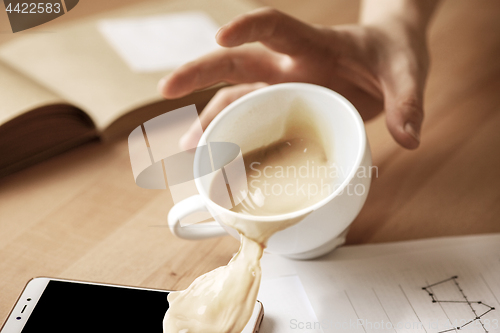 Image of Coffee in white cup spilling on the table in the morning working day at office table