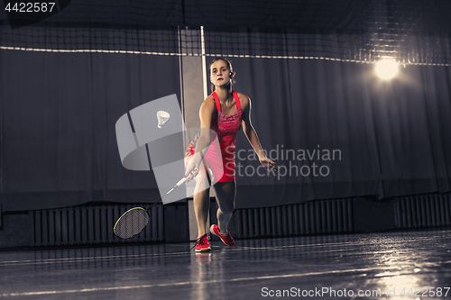 Image of Young woman playing badminton at gym