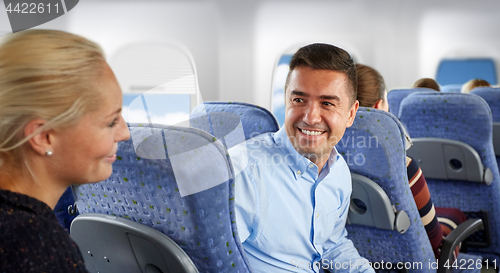 Image of happy passengers talking in plane