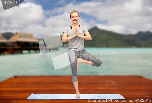 Image of woman making yoga in tree pose outdoors