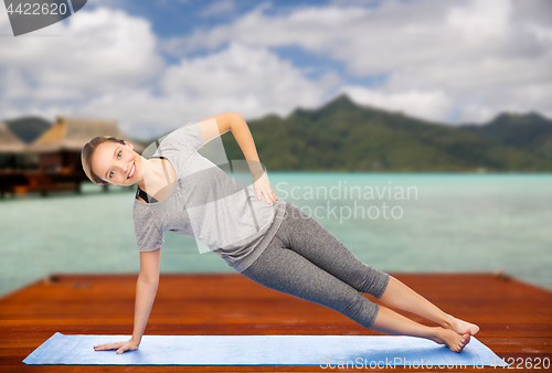 Image of woman making yoga in side plank pose outdoors