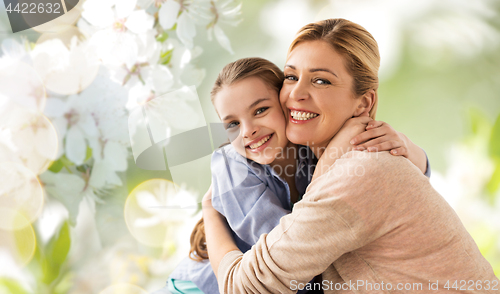 Image of happy mother hugging daughter over cherry blossom