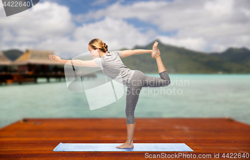 Image of woman making yoga lord of the dance pose outdoors