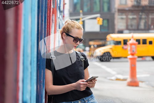 Image of Woman using smartphones against colorful graffiti wall in New York city, USA.