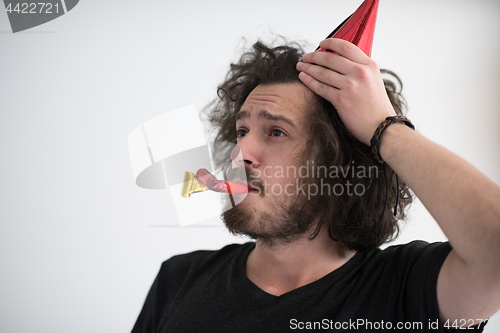 Image of Portrait of a man in party hat blowing in whistle