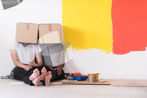 Image of young multiethnic couple playing with cardboard boxes