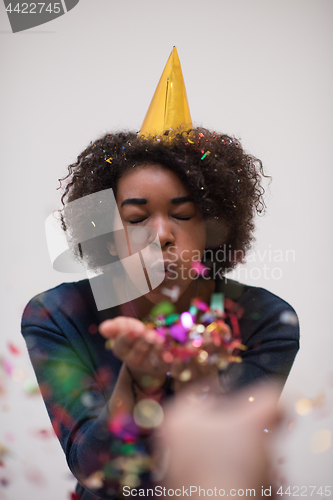 Image of African American woman blowing confetti in the air