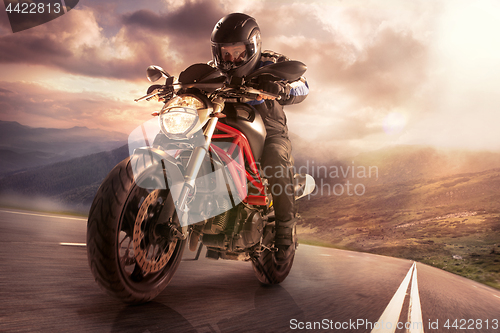Image of biker on mountain highway, riding around a curve with a motion b