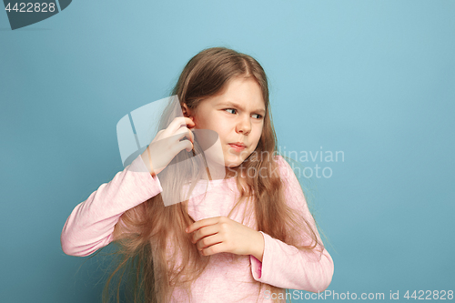 Image of The Ear ache. Teen girl on a blue background. Facial expressions and people emotions concept