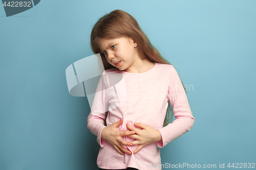 Image of The abdominal pain. Teen girl on a blue background. Facial expressions and people emotions concept