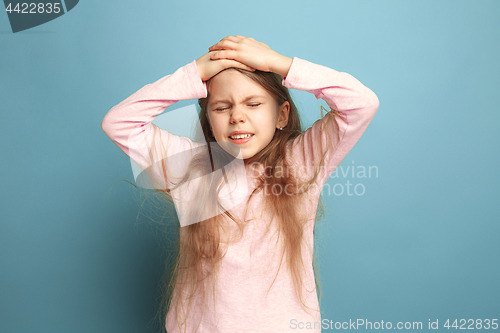 Image of The headache. Teen girl on a blue background. Facial expressions and people emotions concept