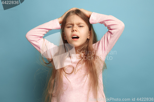 Image of The headache. Teen girl on a blue background. Facial expressions and people emotions concept