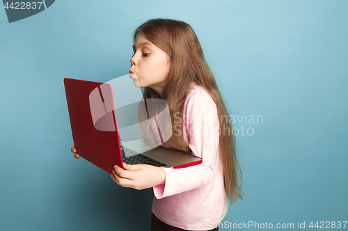 Image of The love of the computer. Teen girl with notebook on a blue background. Facial expressions and people emotions concept