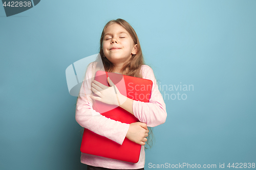 Image of The love of the computer. Teen girl with notebook on a blue background. Facial expressions and people emotions concept