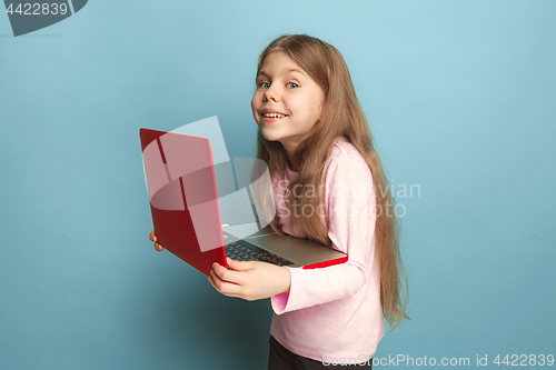 Image of The love of the computer. Teen girl with notebook on a blue background. Facial expressions and people emotions concept