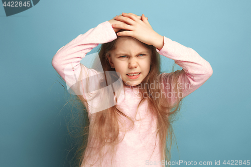 Image of The headache. Teen girl on a blue background. Facial expressions and people emotions concept