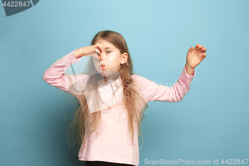 Image of The disgust. Teen girl on a blue background. Facial expressions and people emotions concept