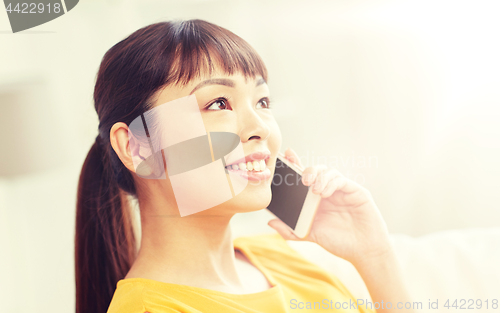 Image of happy asian woman calling on smartphone at home
