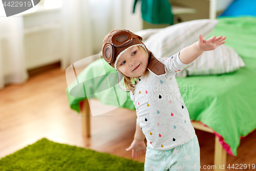 Image of happy little girl in pilot hat playing at home