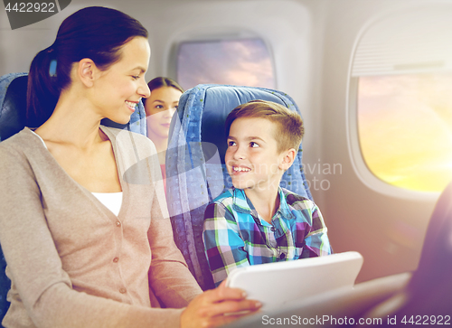 Image of happy family with tablet pc sitting in plane