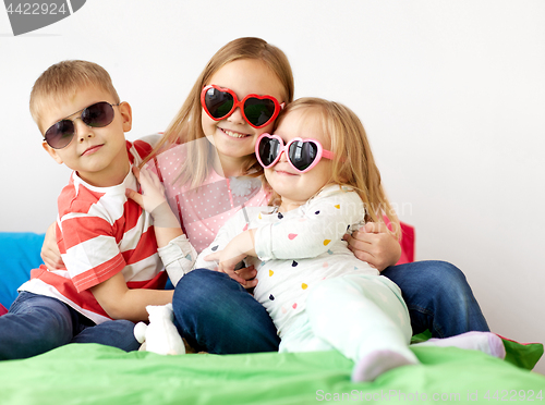 Image of happy little kids in sunglasses at home