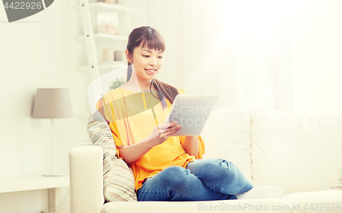 Image of happy young asian woman with tablet pc at home