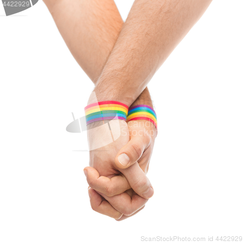 Image of hands of couple with gay pride rainbow wristbands